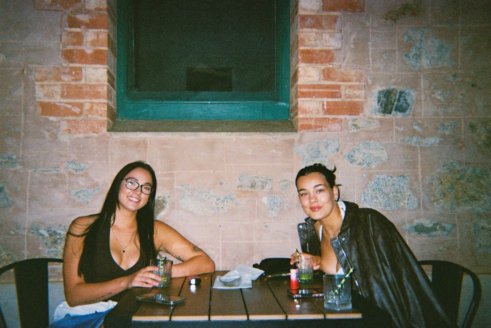 Two friends with drinks at a courtyard table at Mary's Bar